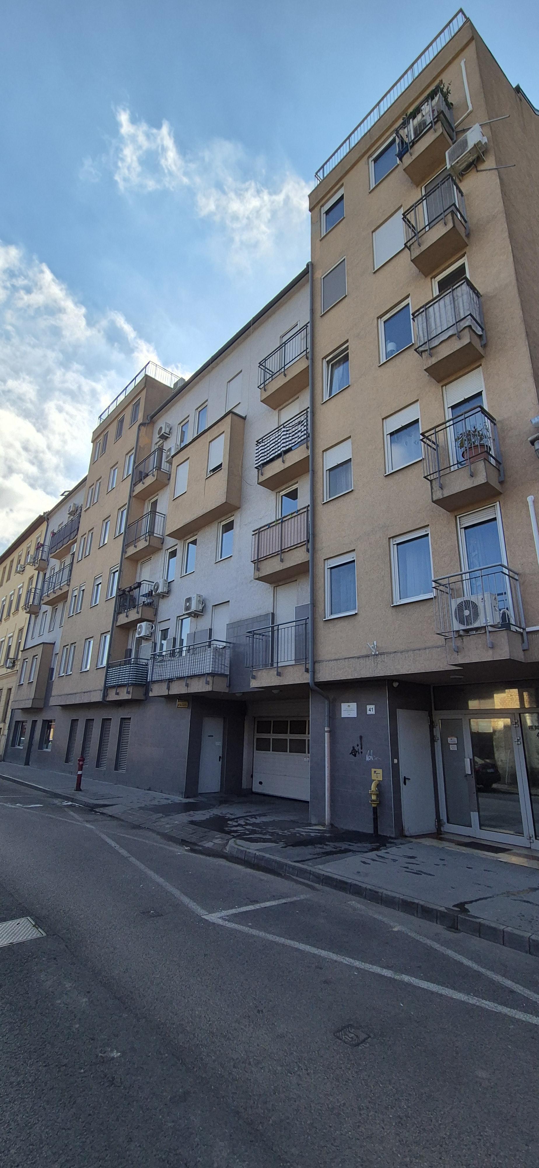 A társasház homlokzata az utcáról, erkélyekkel és garázsbejárattal