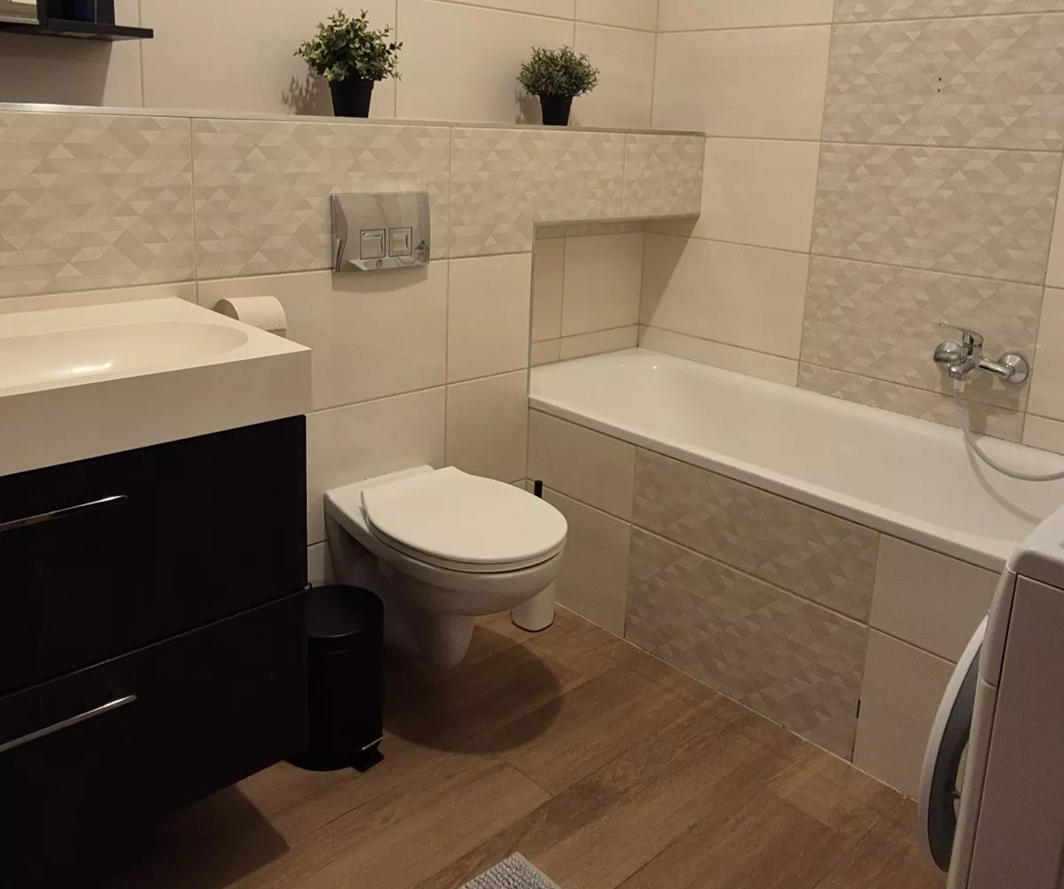 Kád, fali WC és fiókos mosdószekrény a fürdőszobában